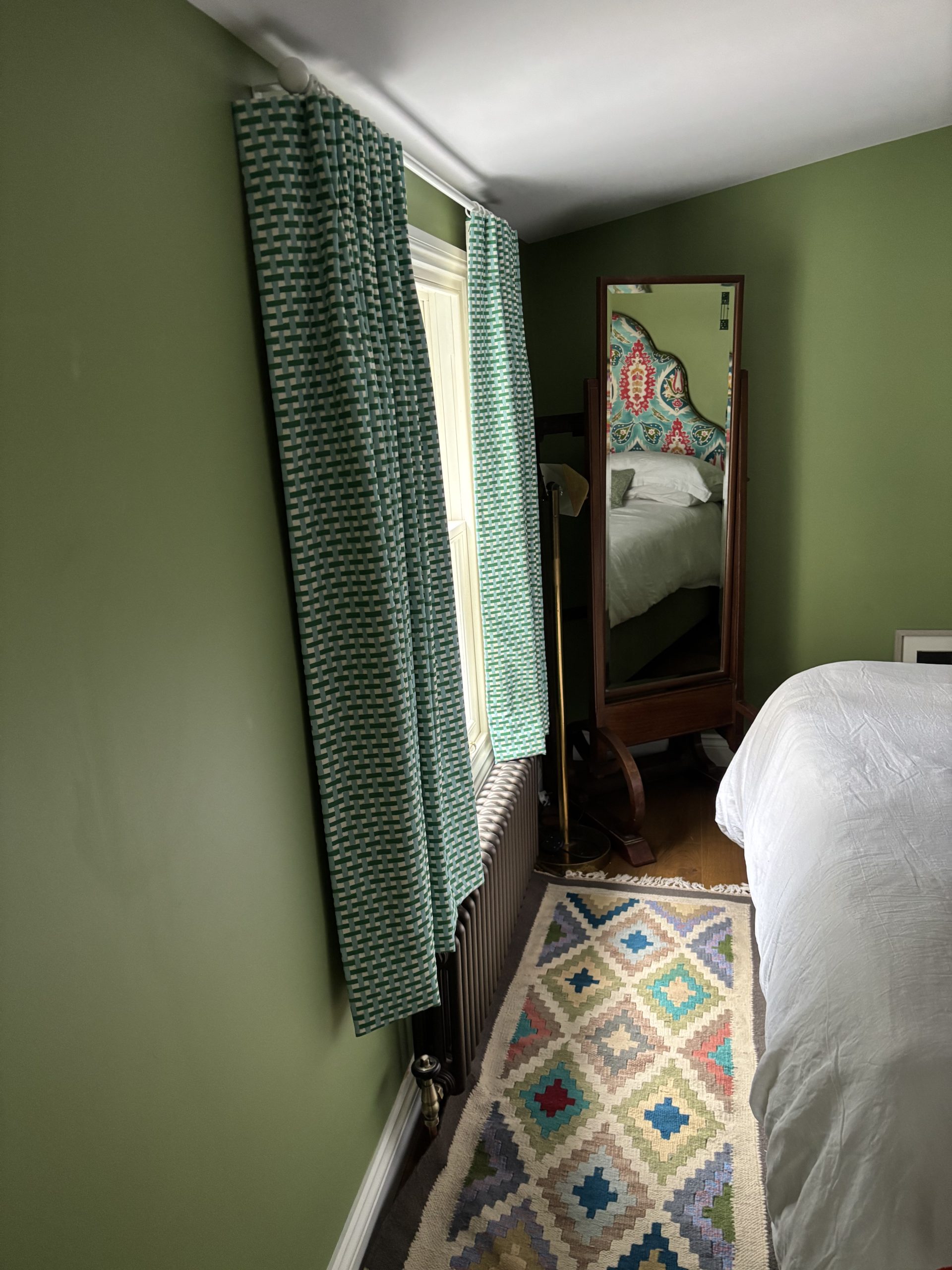 Bedroom painted green with rug on floor and bespoke curtains by Fiona Lawson Design