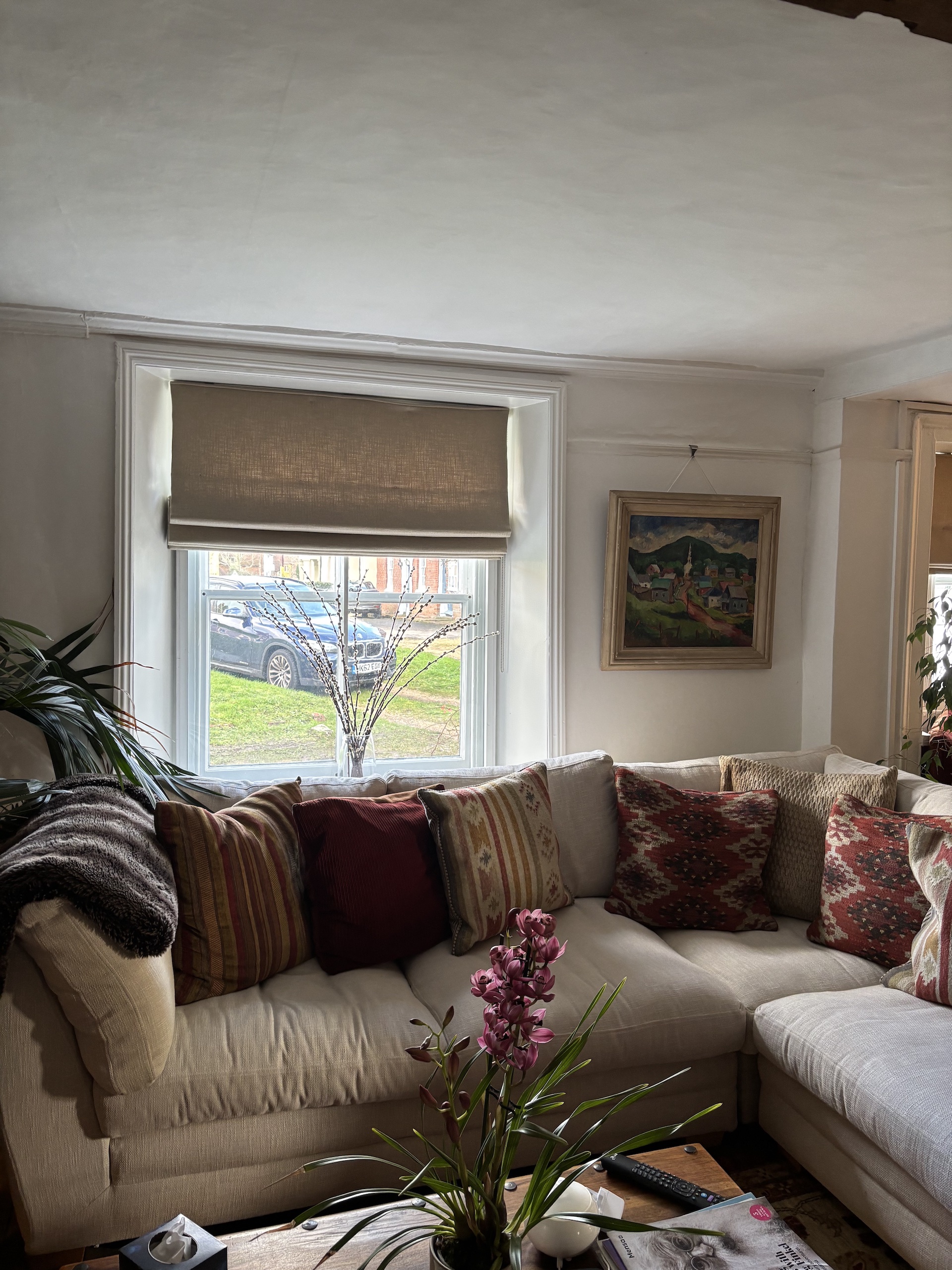 Sofa with lots of cushions, with window in background with blind. Work by Fiona Lawson Design.