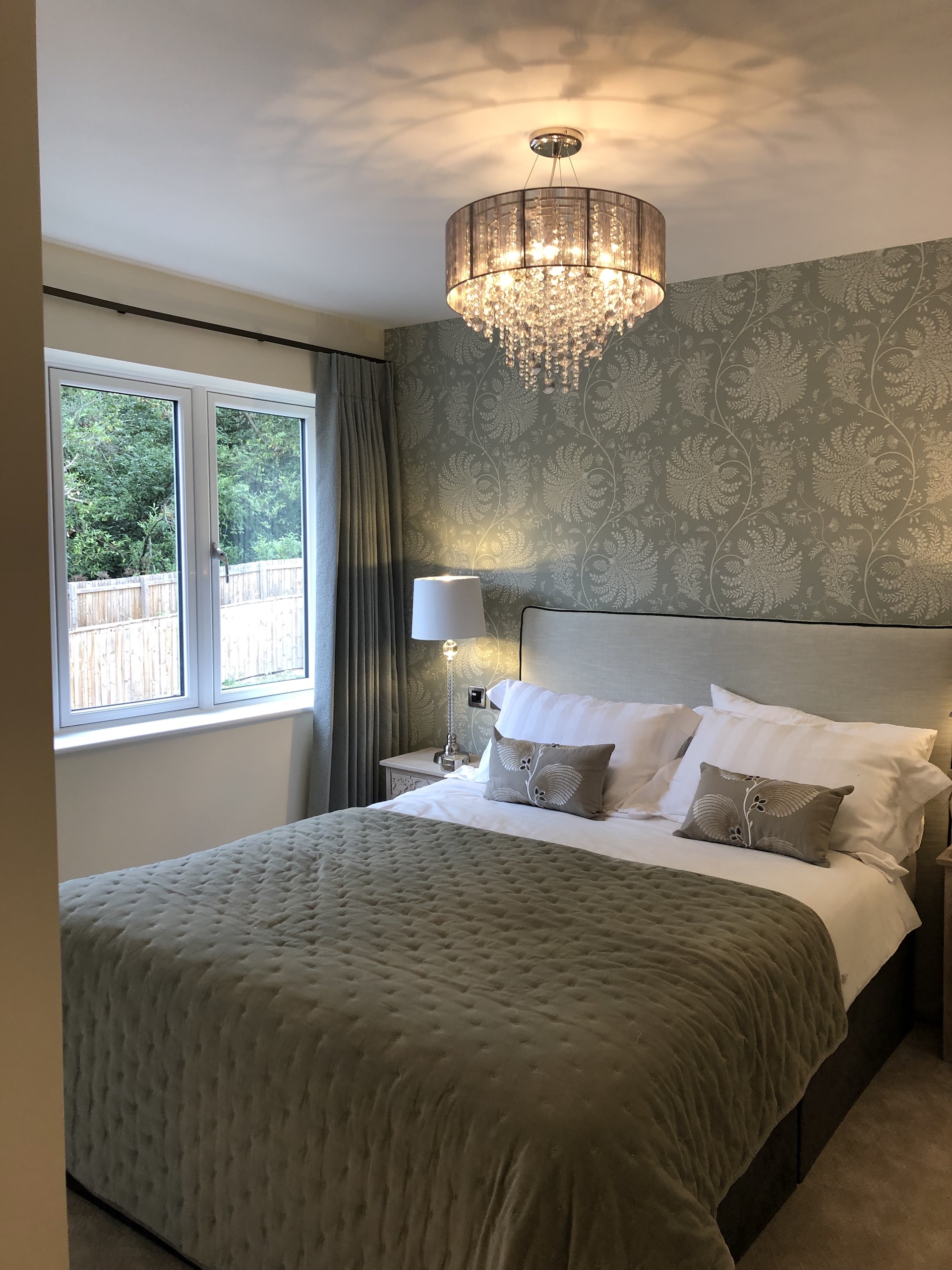 Bedroom with dressed bed and wallpaper behind the bed. Interior Design by Fiona Lawson Design.